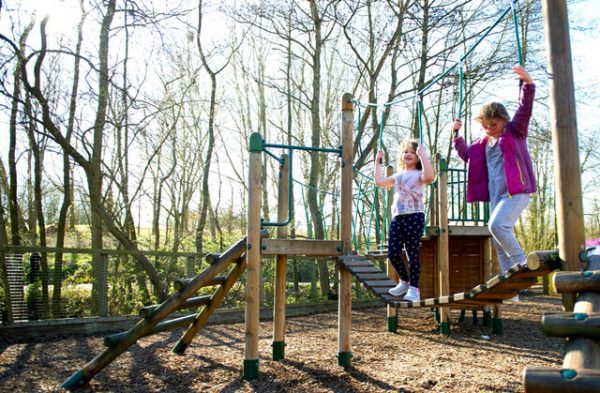 Children playing together on a timber play bridge